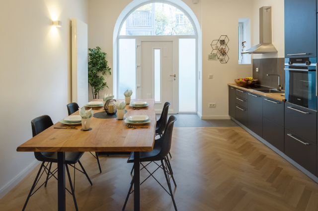 moderne offene Küche mit Essbereich bestehend aus schwarzen Flächen in Kombination mit Holzelementen
